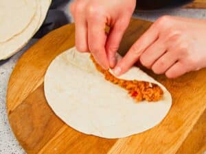 hand rolling tortilla around chickpea and sauce