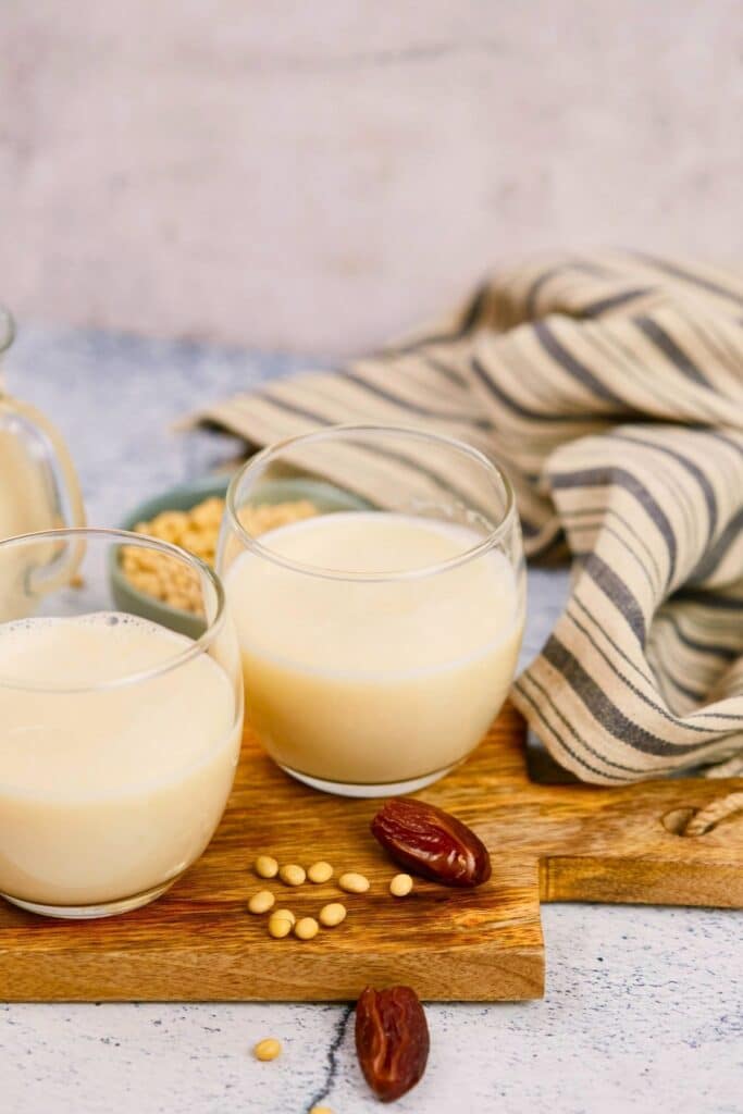 milk in small mugs on table next to striped napkin