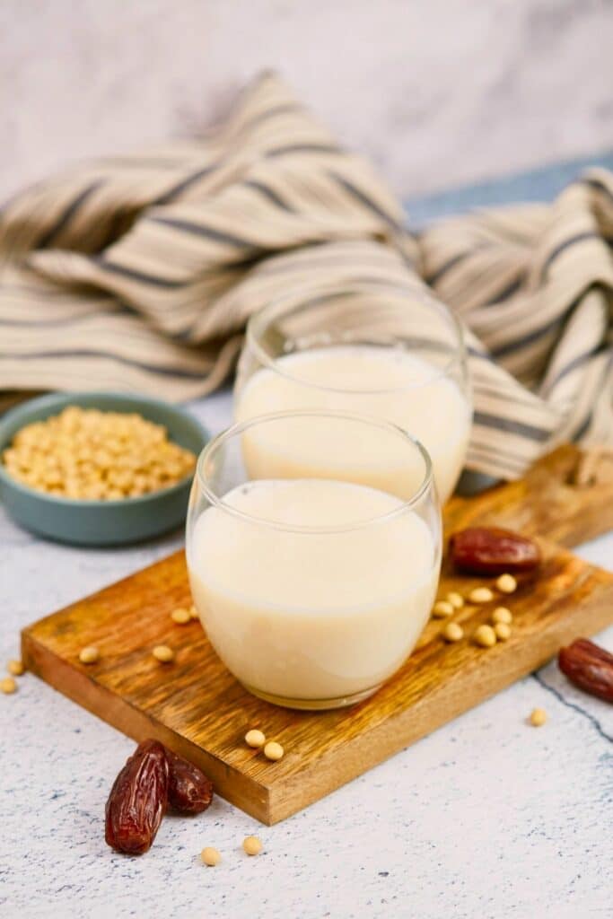 glasses on wood platter holding homemade soy milk