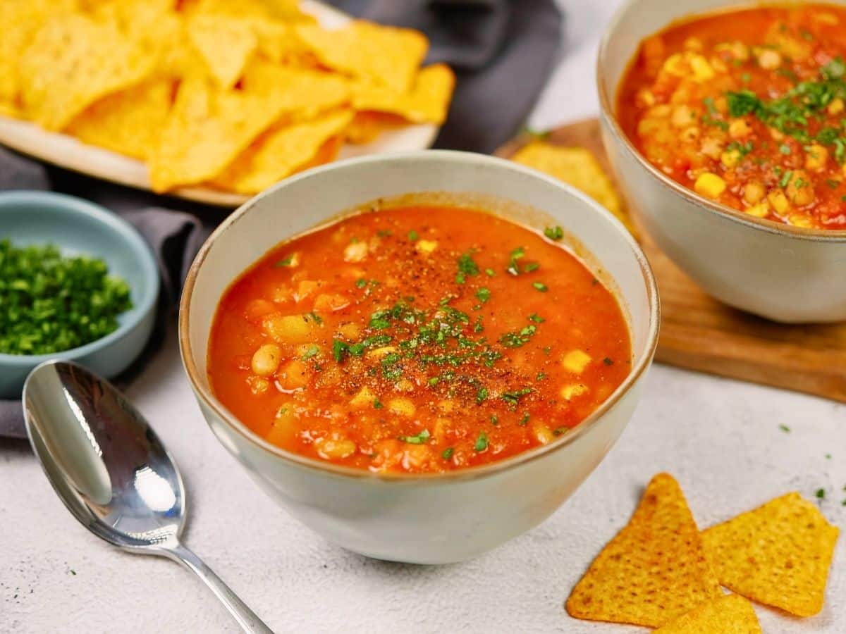 bowl of soup on table by spoon and tortilla chips