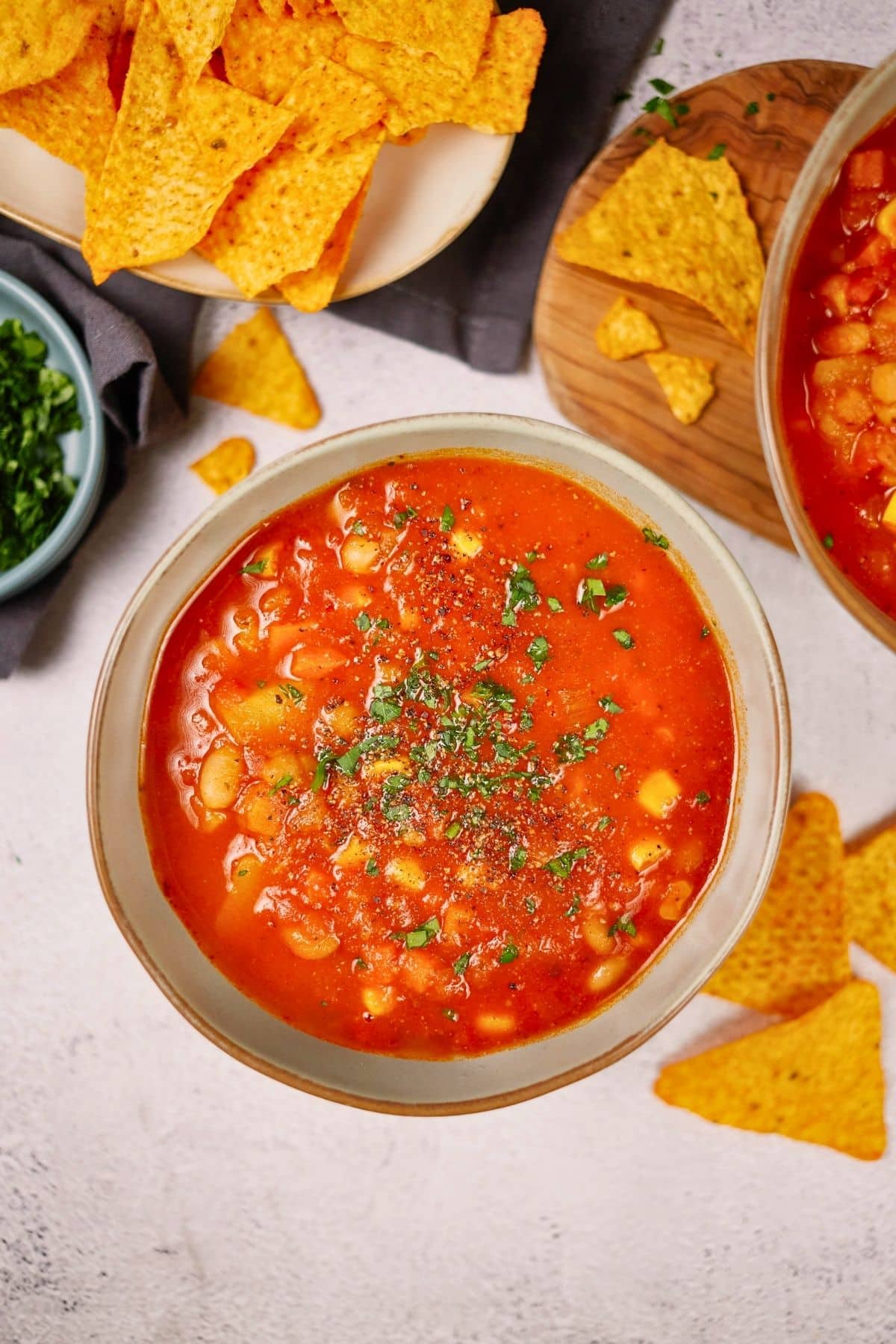 light green bowl of vegan bean soup on table net to chips