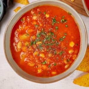 bowl of soup on table by spoon and tortilla chips