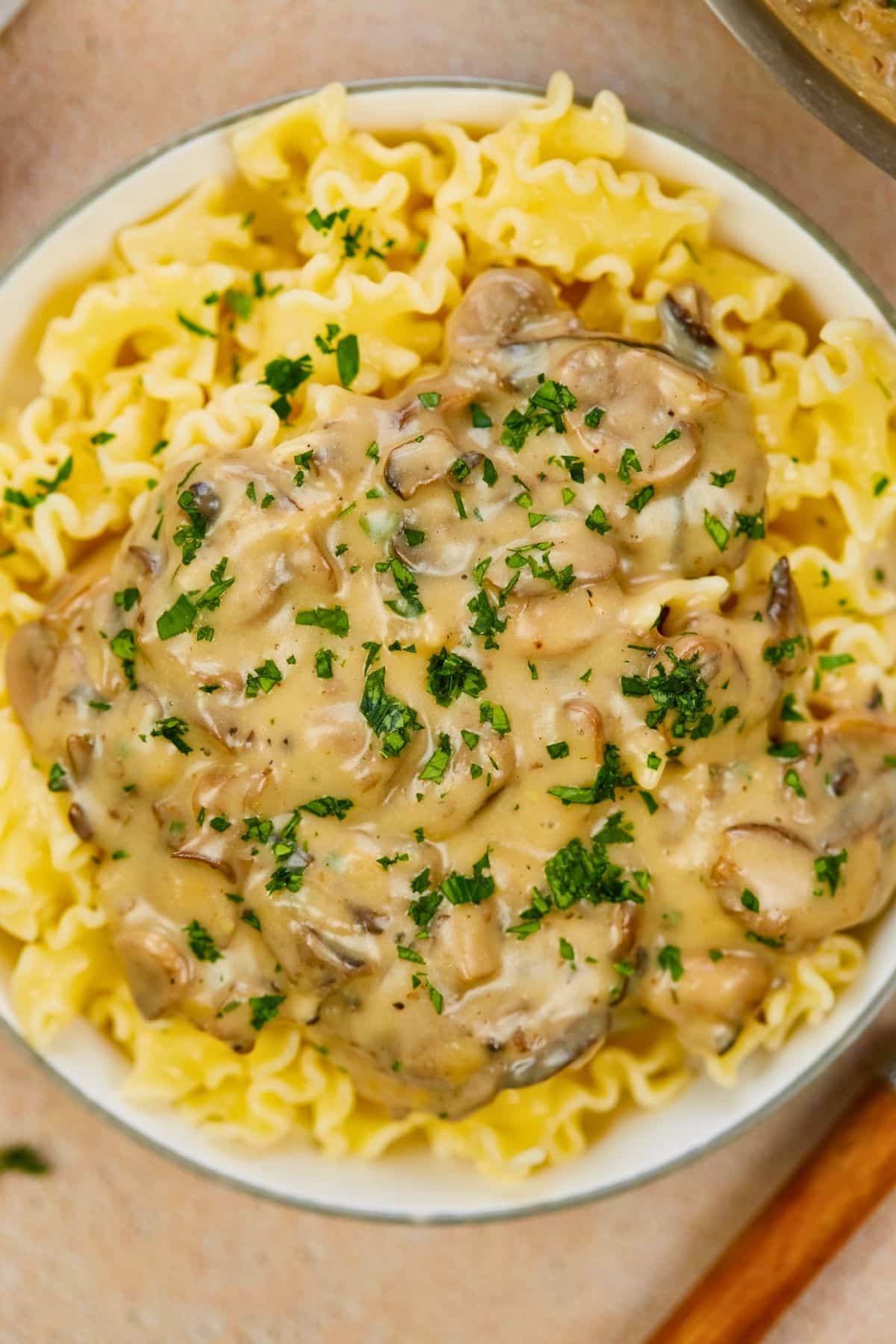 bowl of pasta and mushroom sauce on table with brown placemat