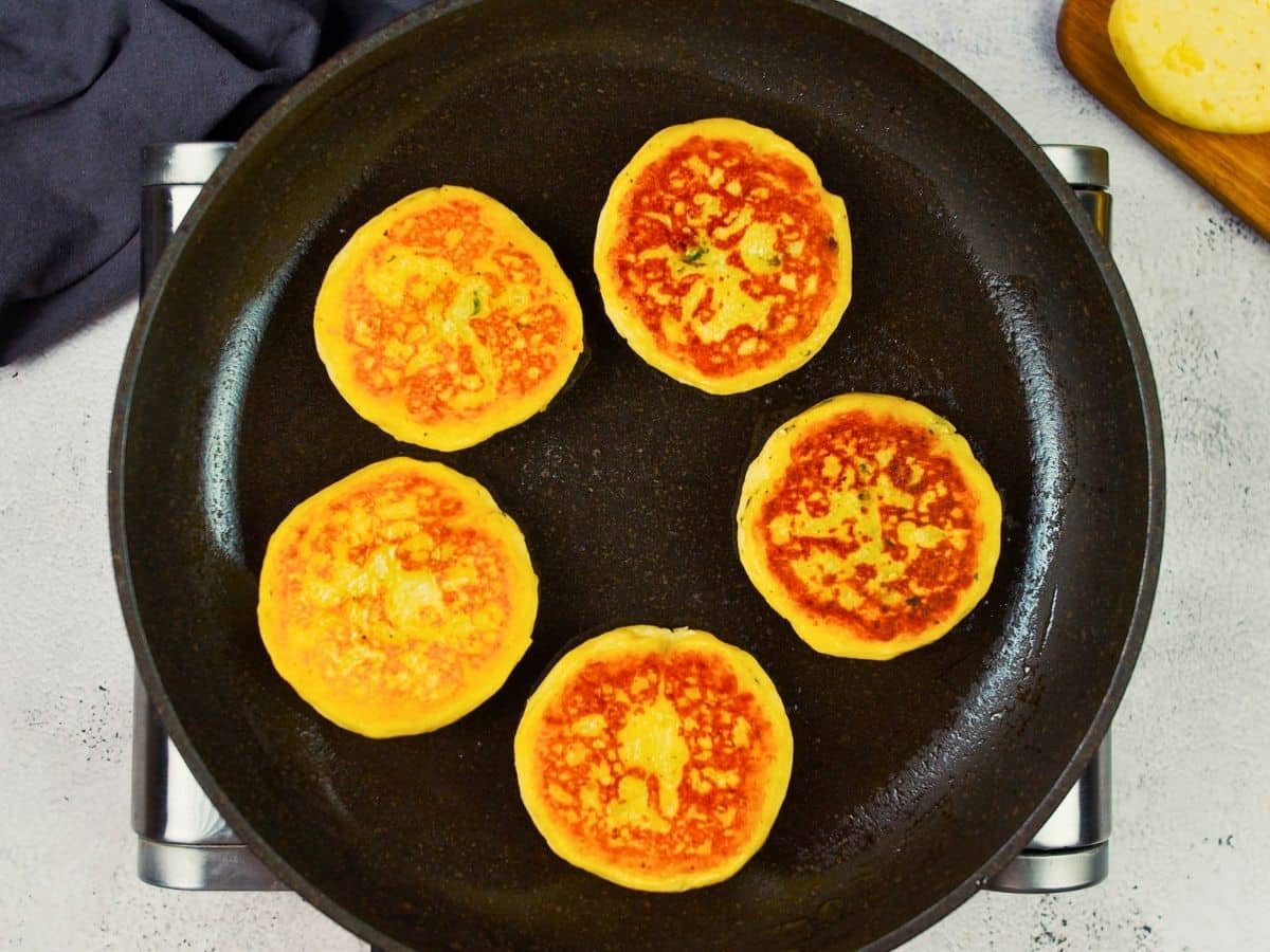 potato cakes cooking in cast iron skillet