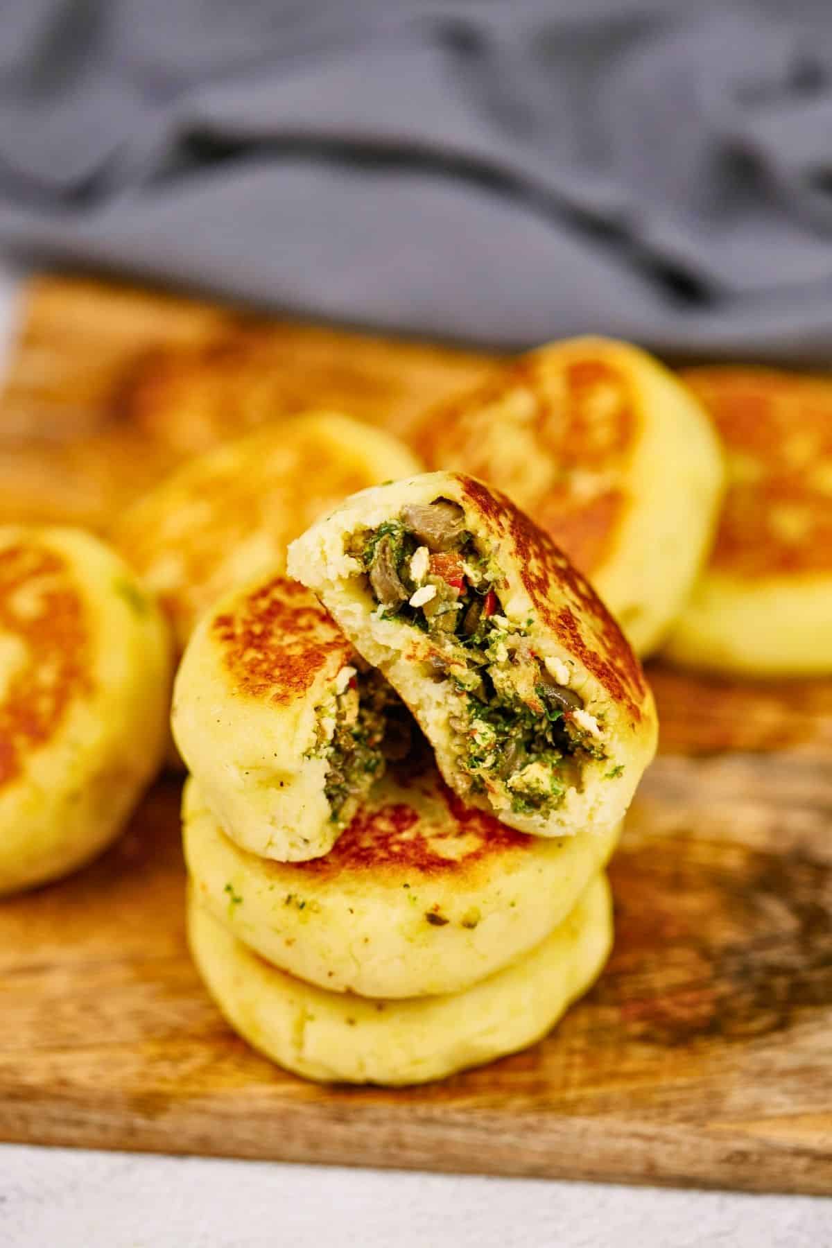 stack of vegan potato cakes on wood cutting board in front of blue napkin