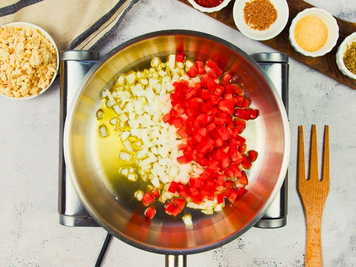 skillet of oil, onions, and peppers on top of hot plate