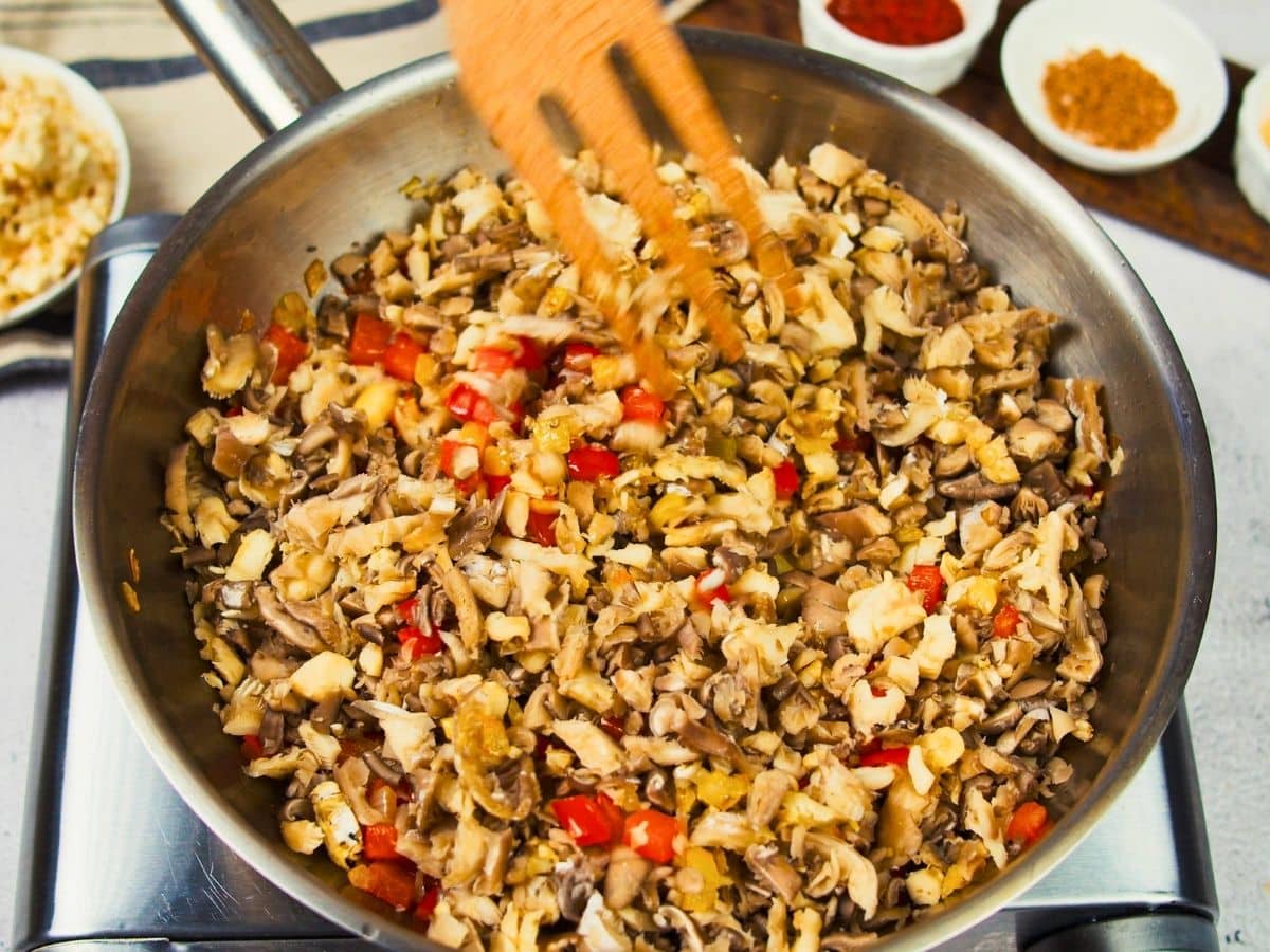 wooden spoon stirring mushrooms in skillet