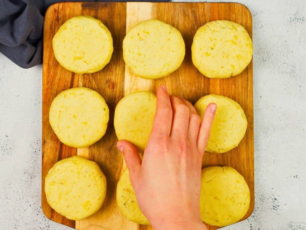 hand placing potato round on cutting board