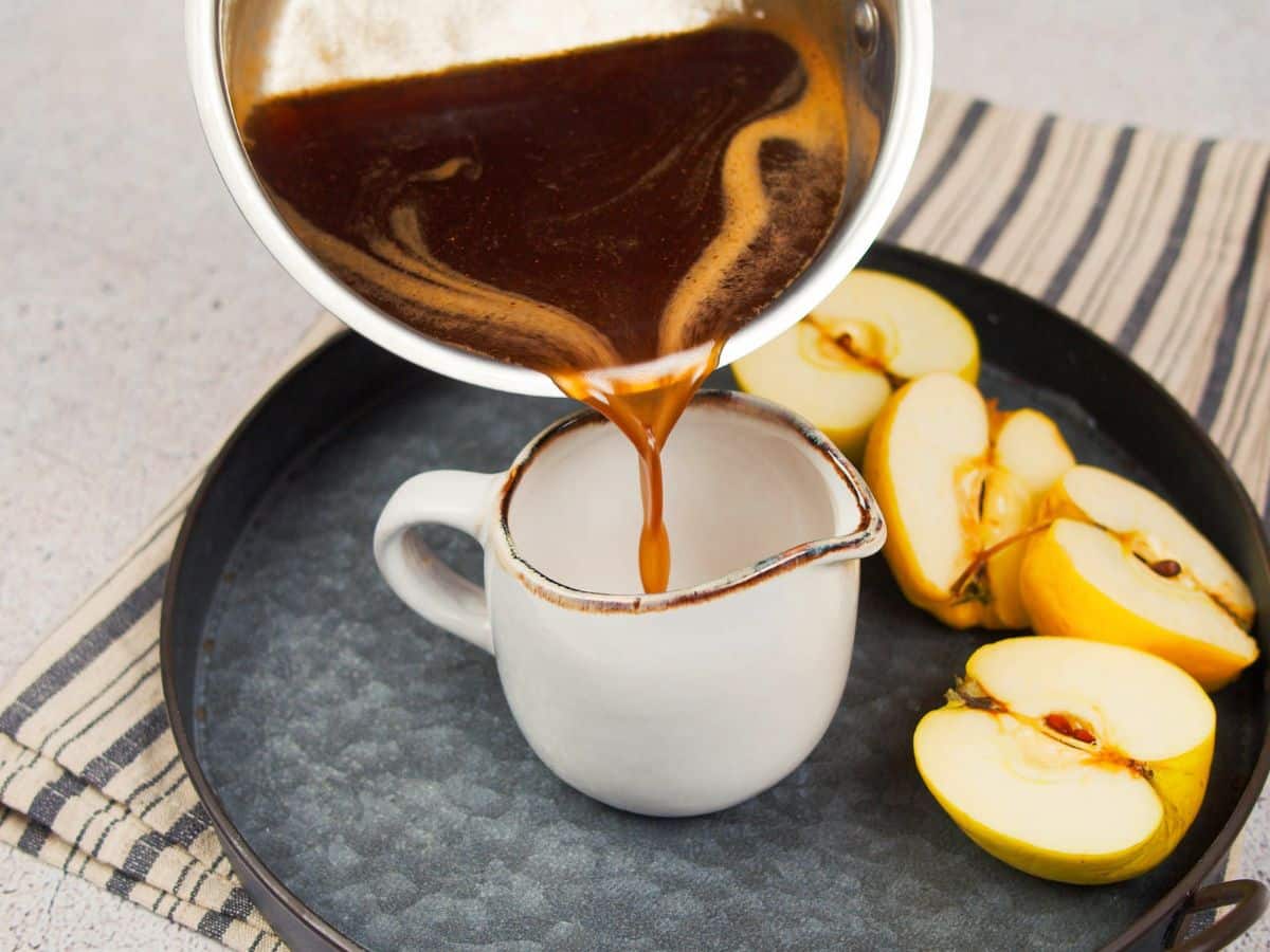 apple cider syrup being poured into white mug on gray late