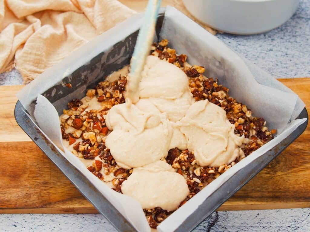 batter being poured over nuts in baking dish