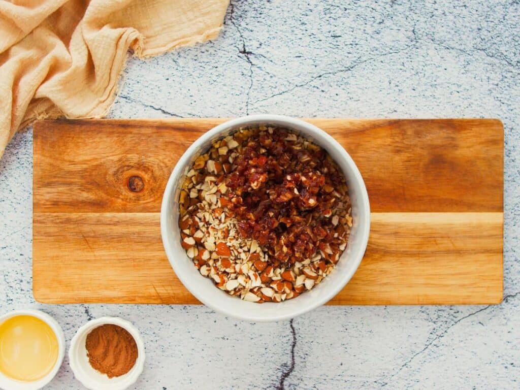 white bowl of nuts on cutting board