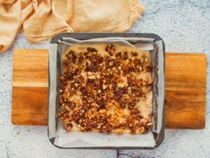 parchment lined square baking dish of batter topped with nuts