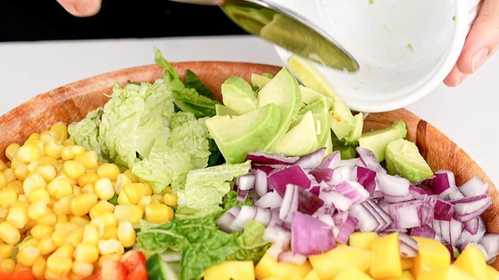 avocado being added to salad bowl