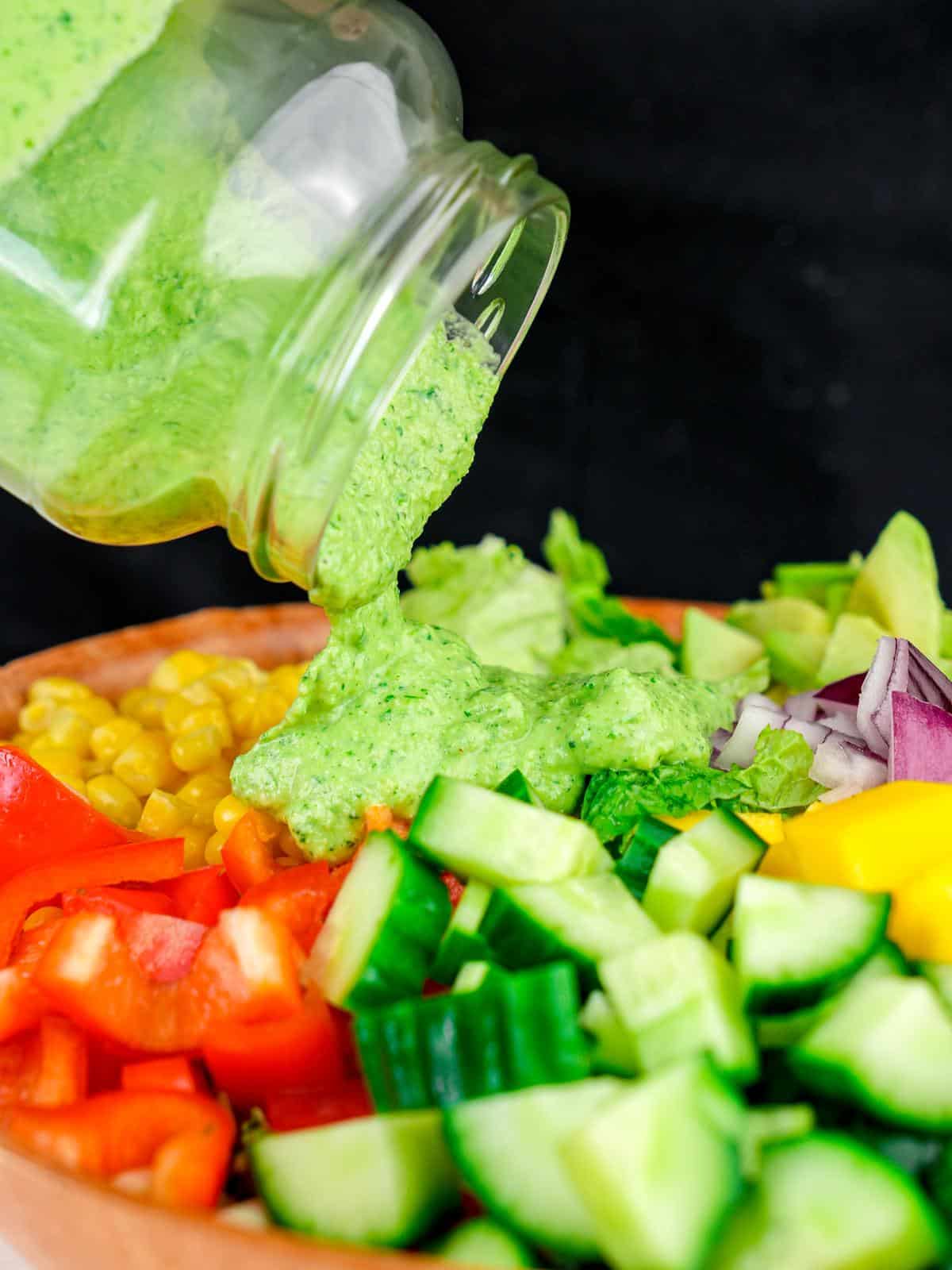 cilantro dressing being poured over avocado mango salad