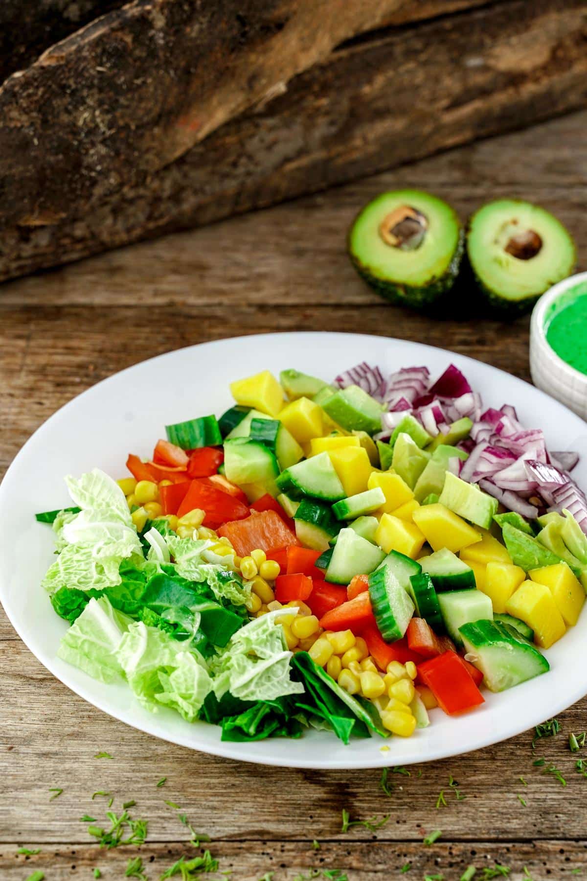 wood table with white plate of avocado mango salad