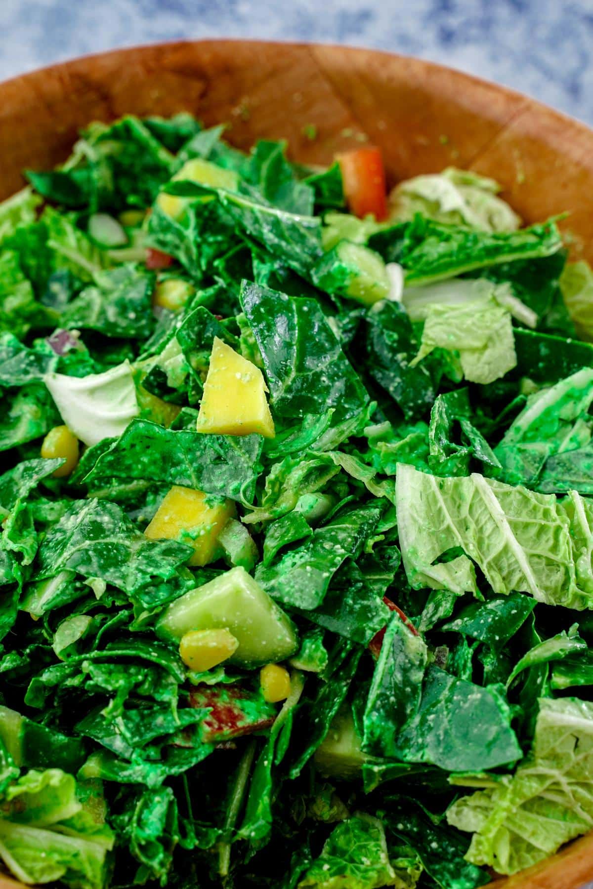 wood bowl of salad on blue table