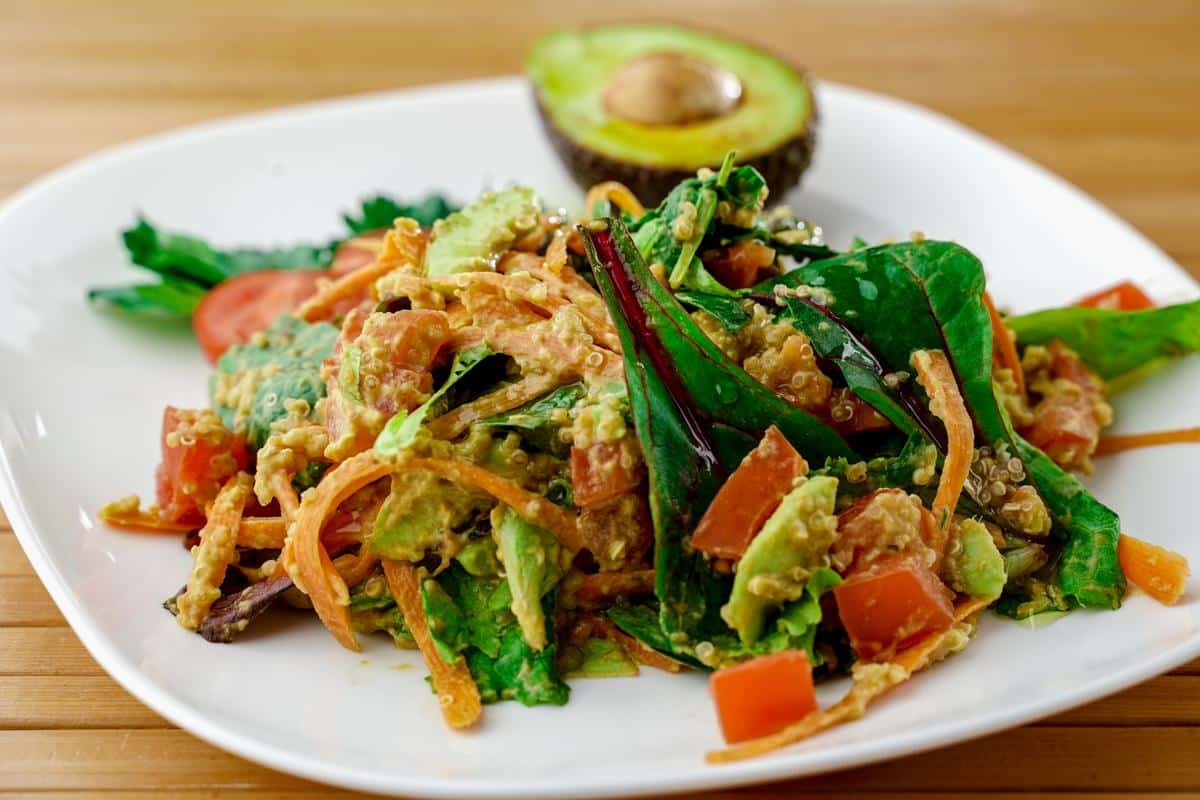 square white plate of avocado quinoa salad with half avocado on edge