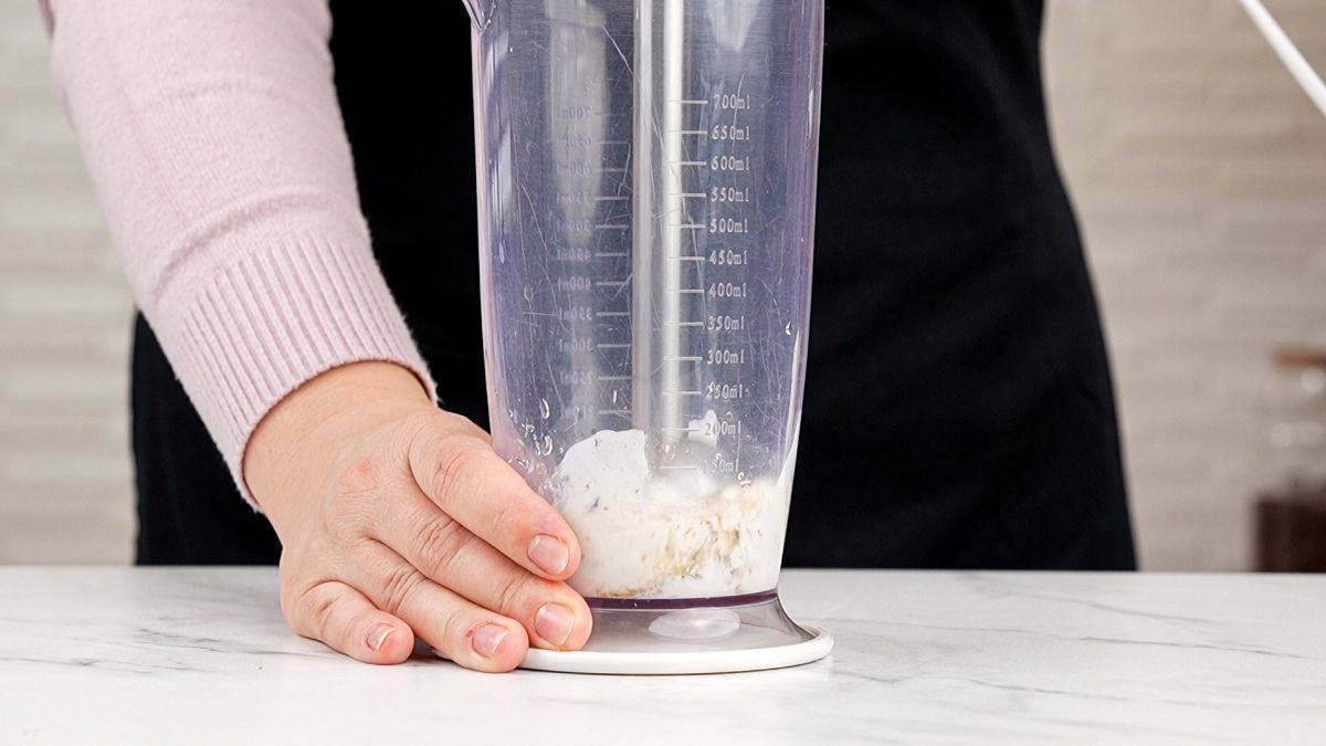 immersion blender in tall container with white sauce