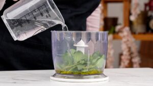 water being poured into food processor with greens