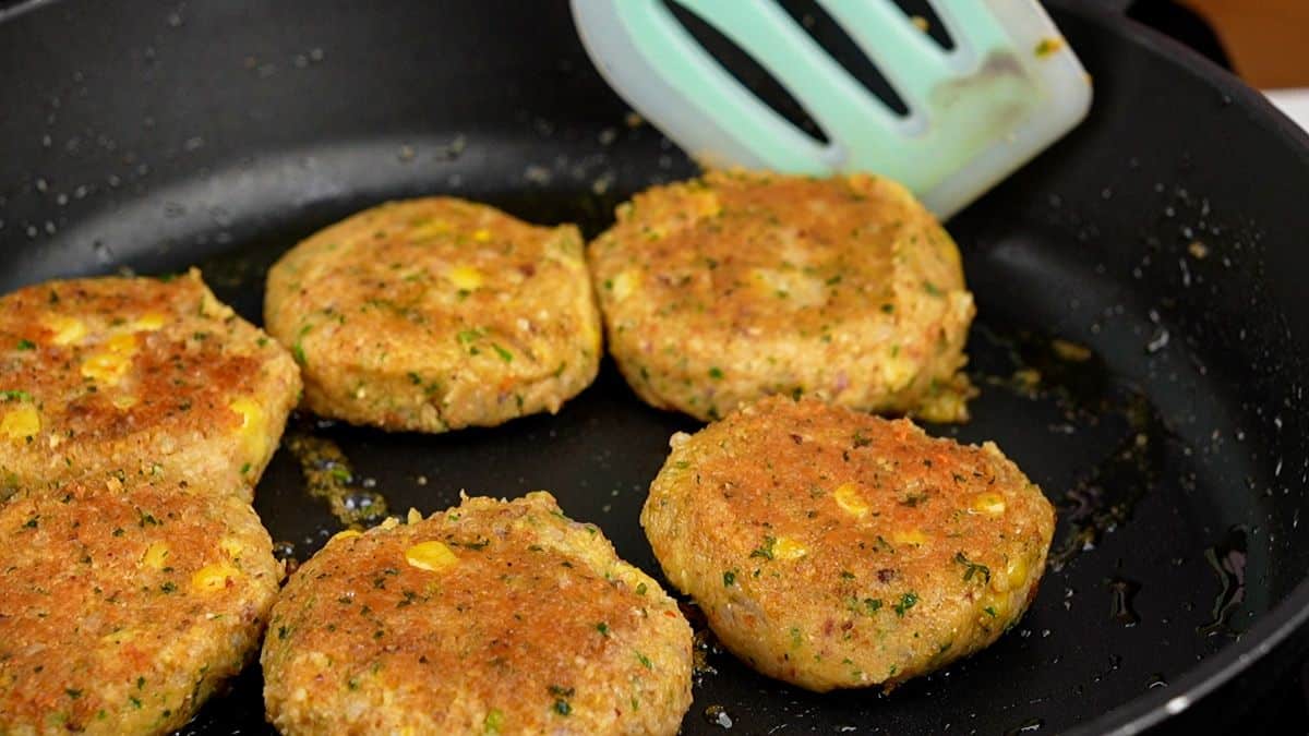 black skillet of chickpea corn patties being cooked