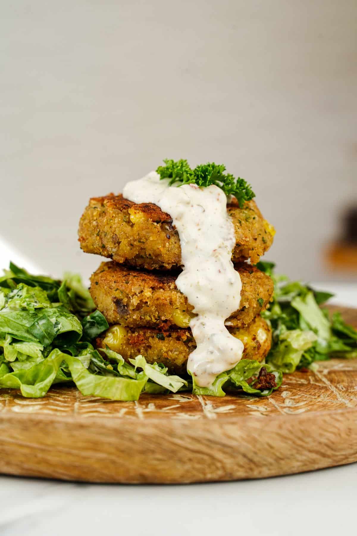 vegan corn patties on plate with sauce and salad