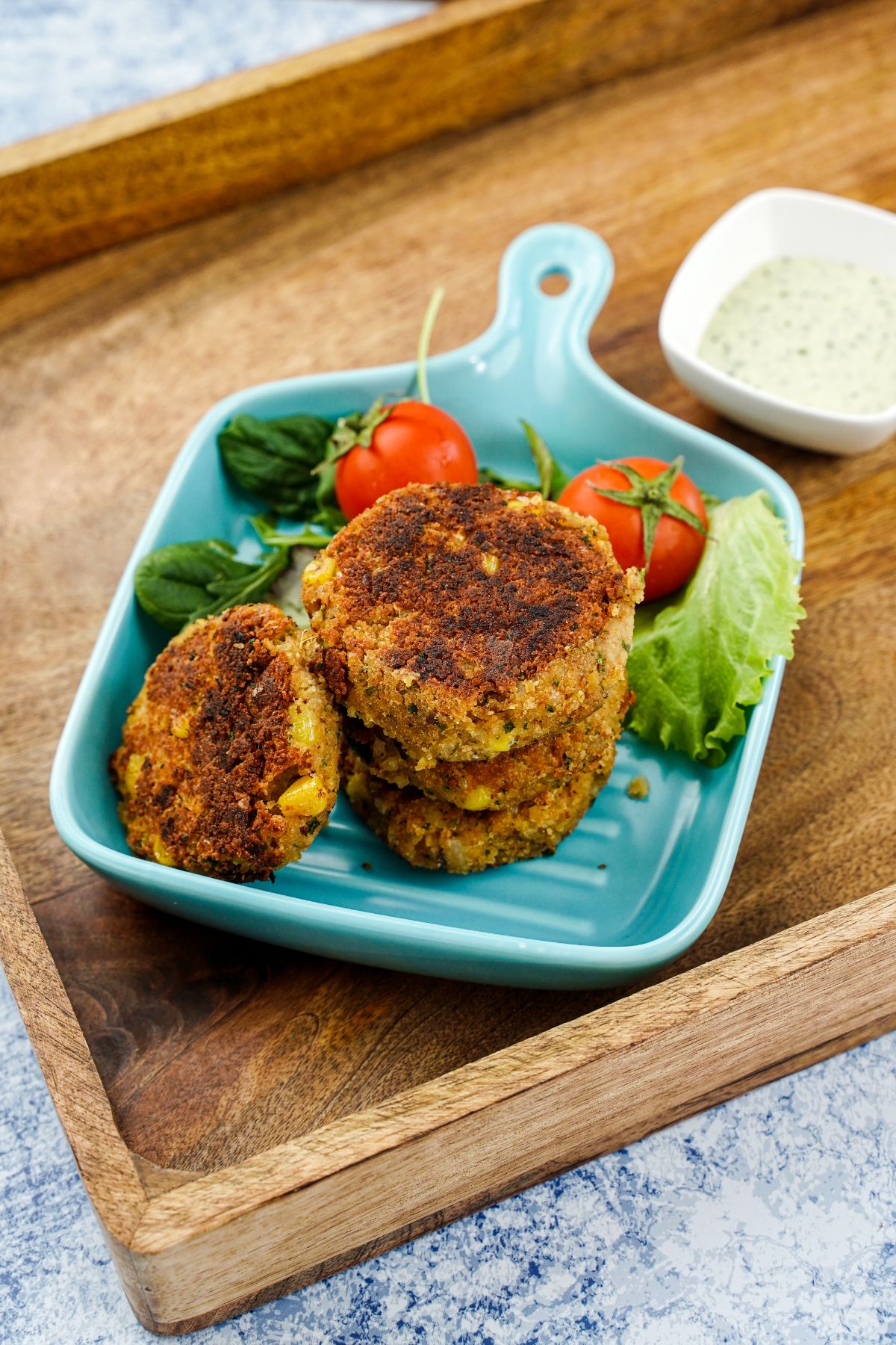fresh tomato and lettuce on plate beside stack of chickpea corn patties