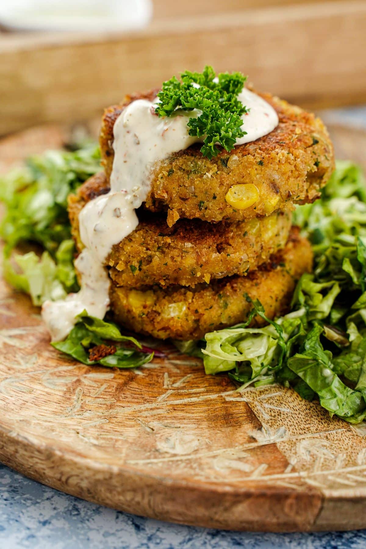 chickpea corn patties stacked on top of salad on wood plate