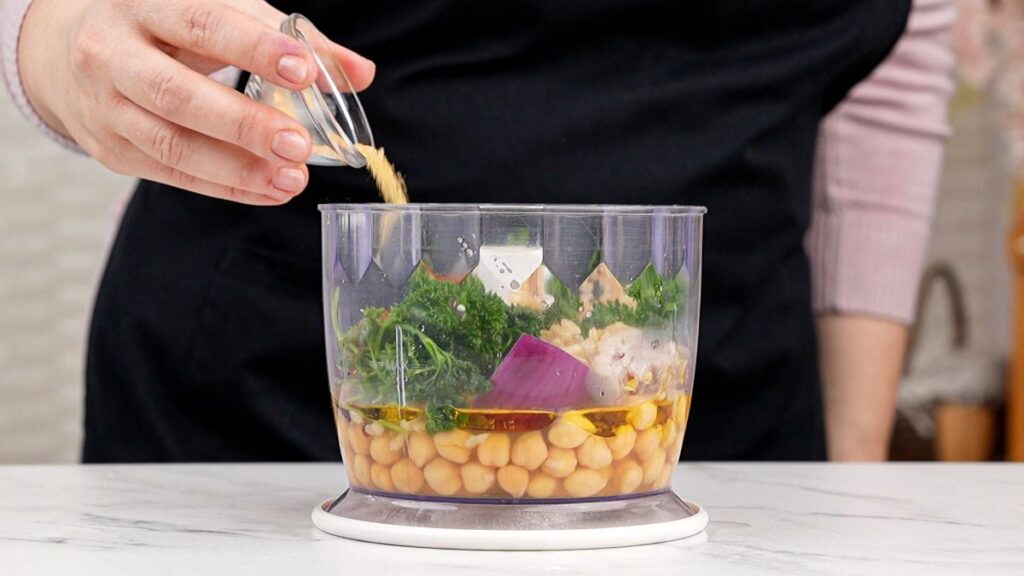 spoon of spices being added to food processor