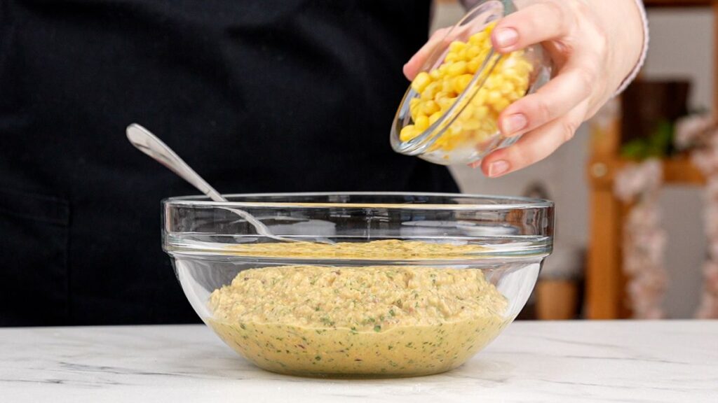 corn being added to bowl of chickpeas