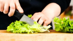 lettuce being chopped on wooden cutting board