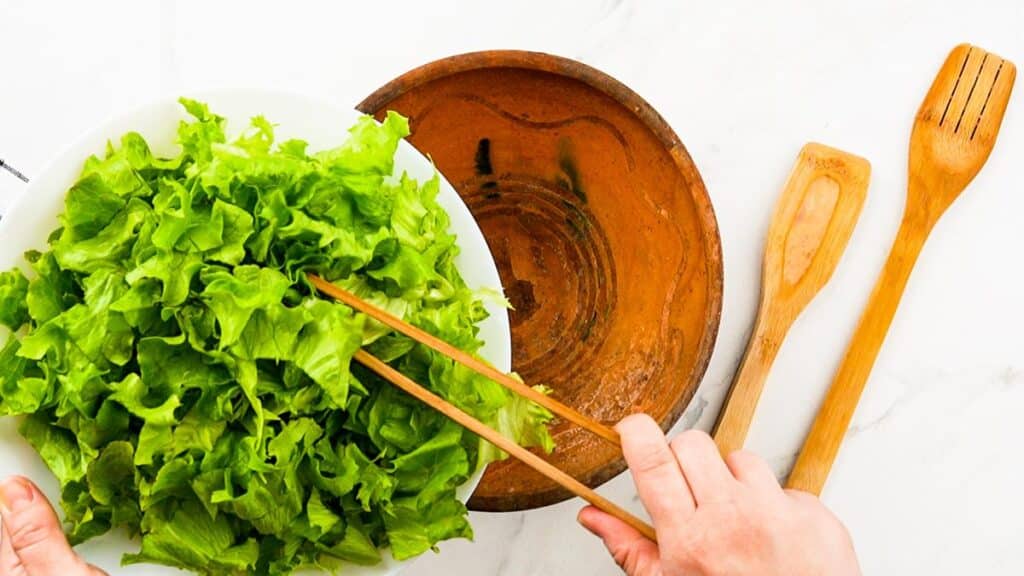 lettuce being poured into wood bowl