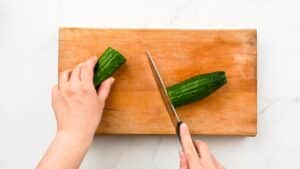 cucumber being sliced on cutting board