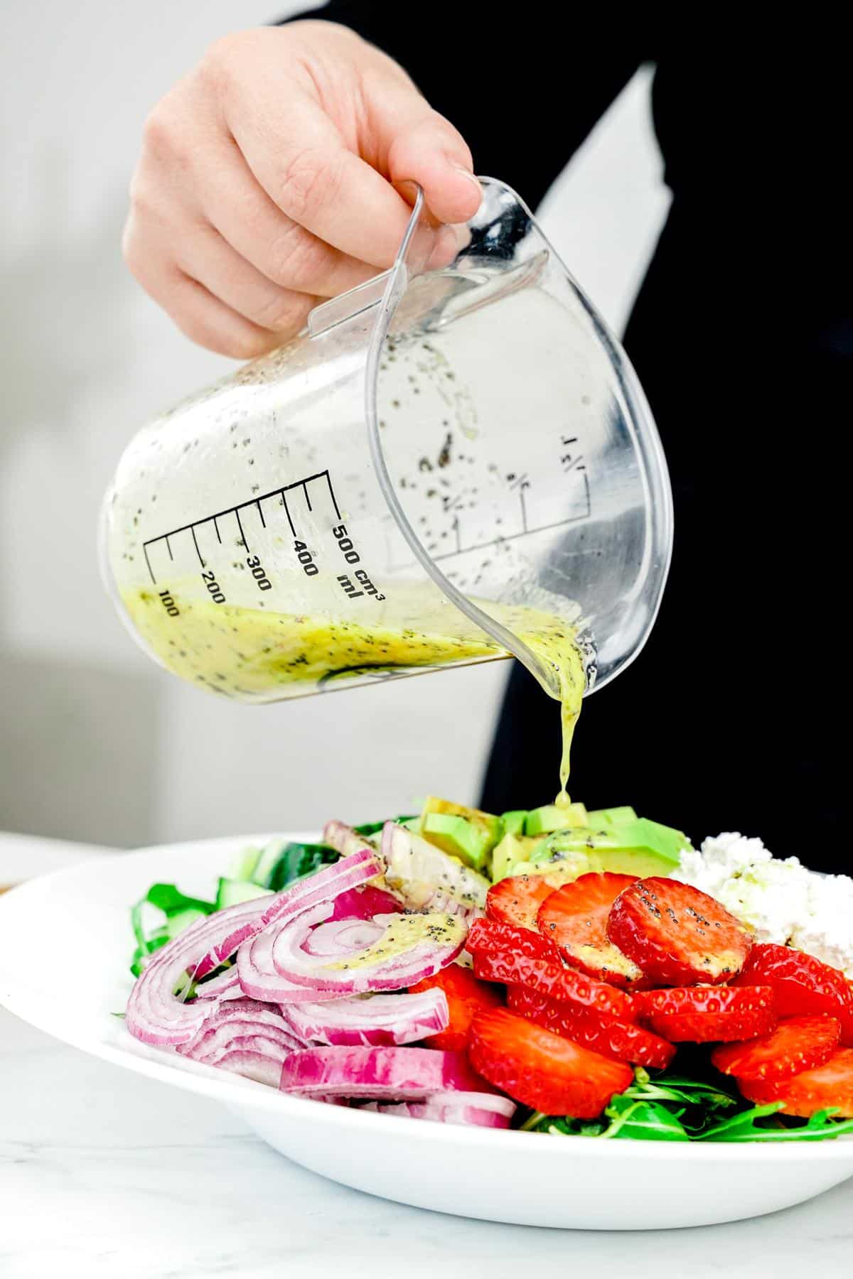 dressing being poured over farro summer salad in white bowl