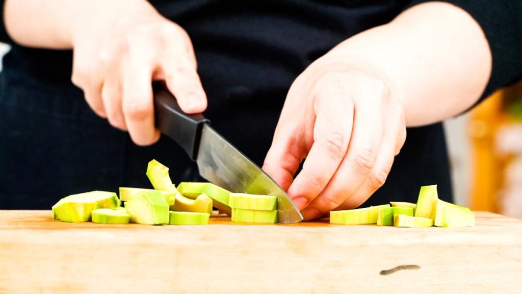 avocado being sliced on cutting board