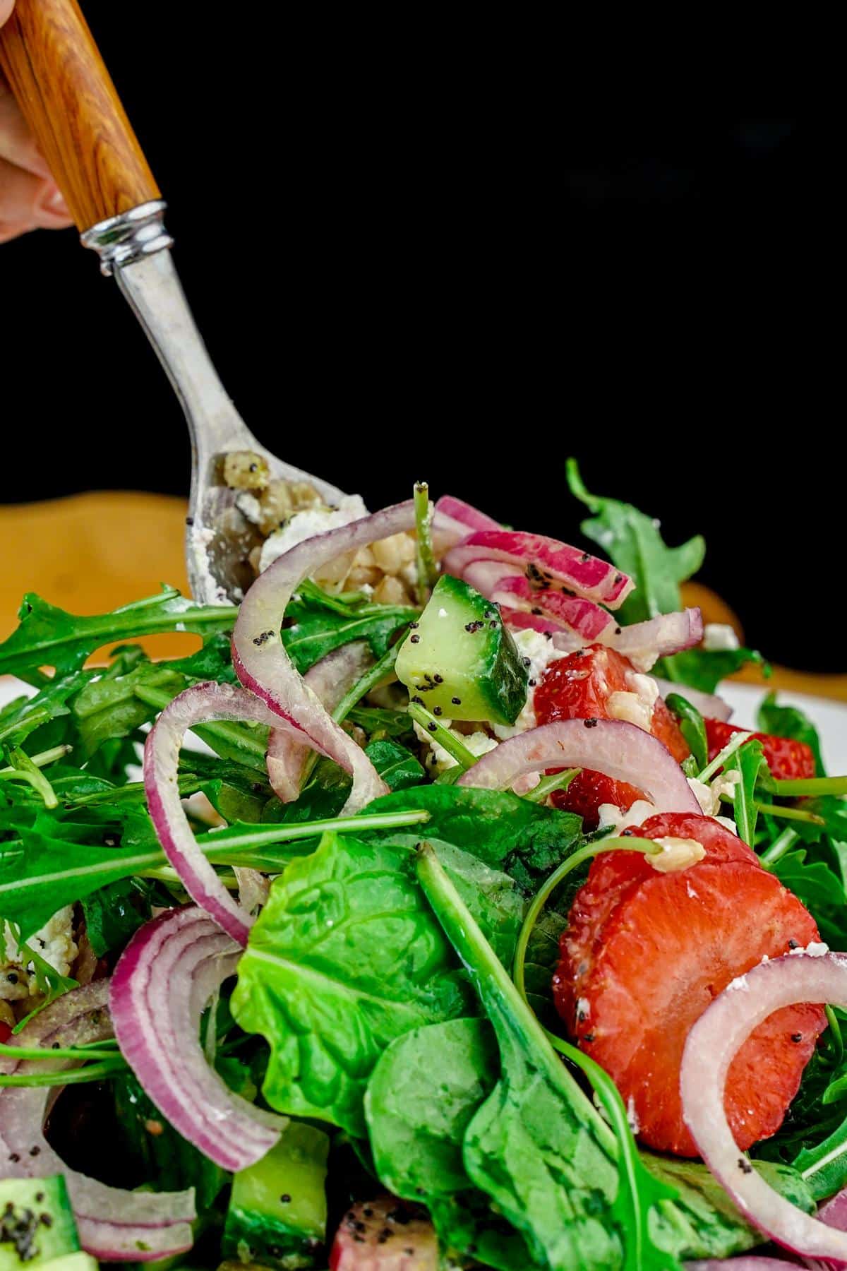 fork in bowl of farro summer salad with red onions and strawberries