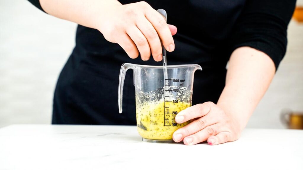 hand mixing dressing in glass measuring cup