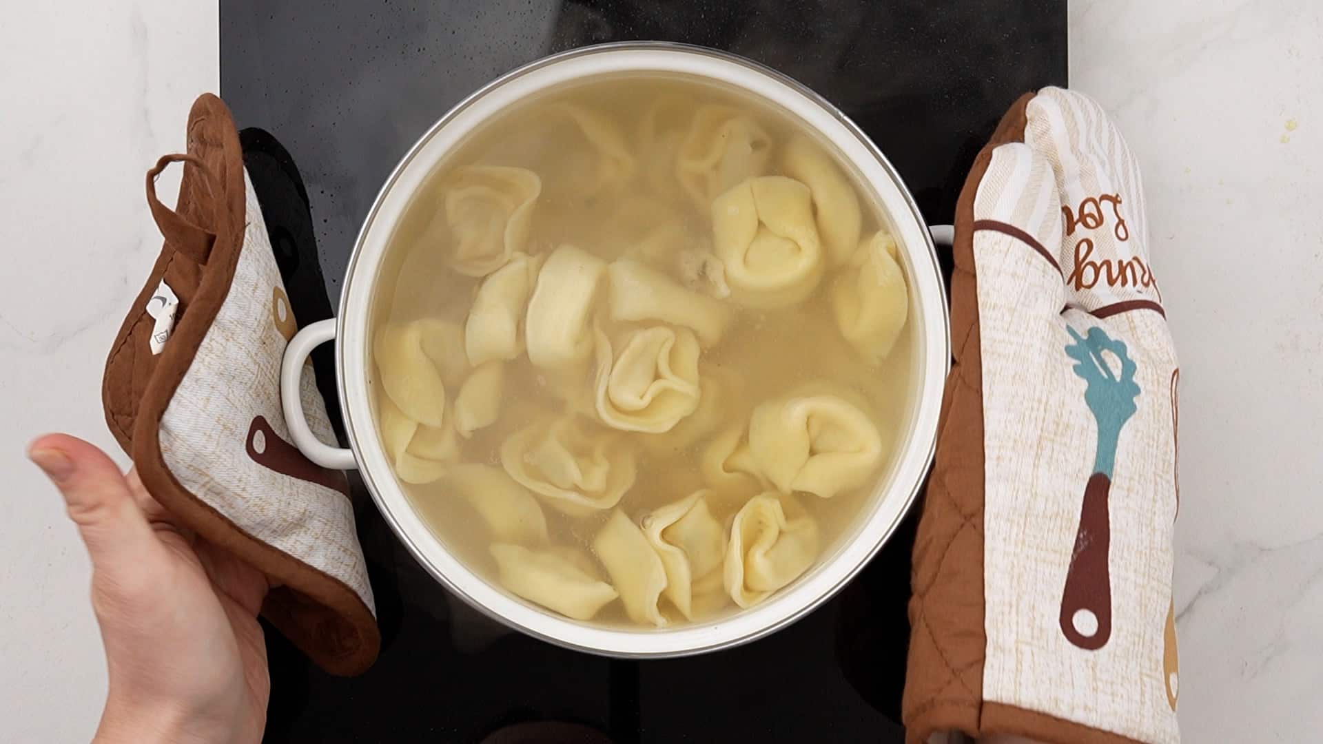 tortellini cooking in saucepan on black hot plate