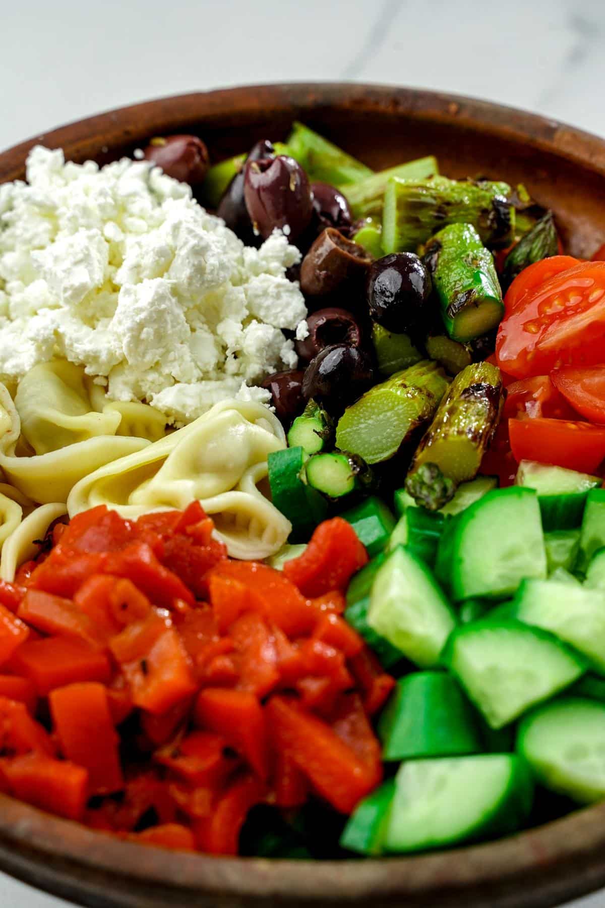 wood bowl of Greek tortellini pasta salad before dressing is added
