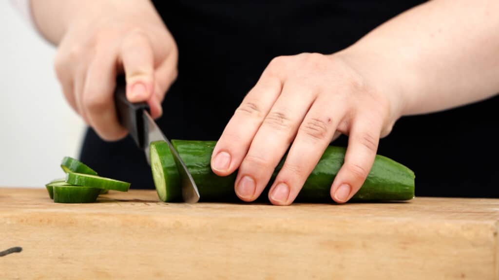 cucumber on cutting board being sliced