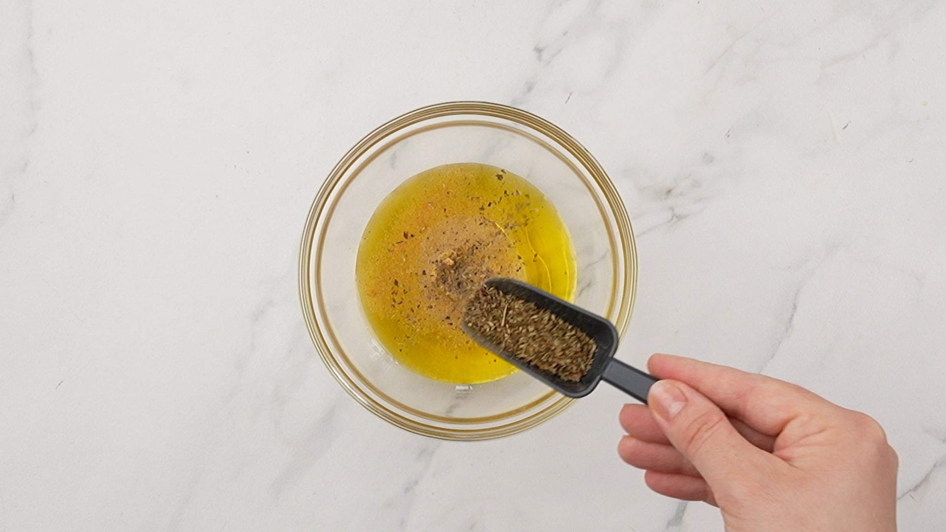seasoning being added to bowl of oil