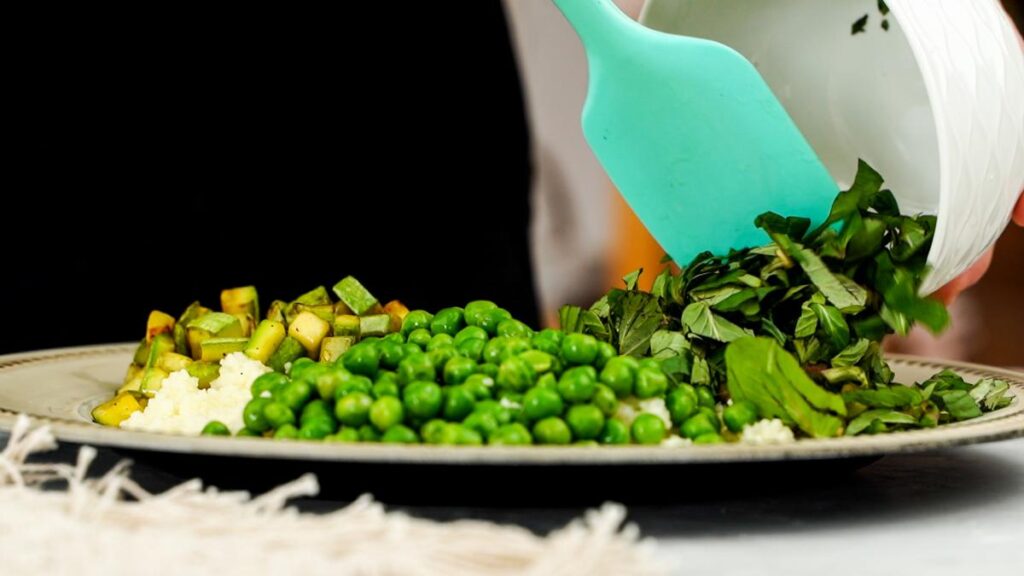 pouring pesto on top of couscous salad