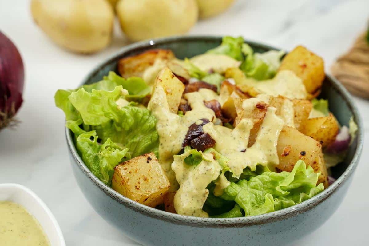 blue bowl of salad with potatoes and tahini dressing