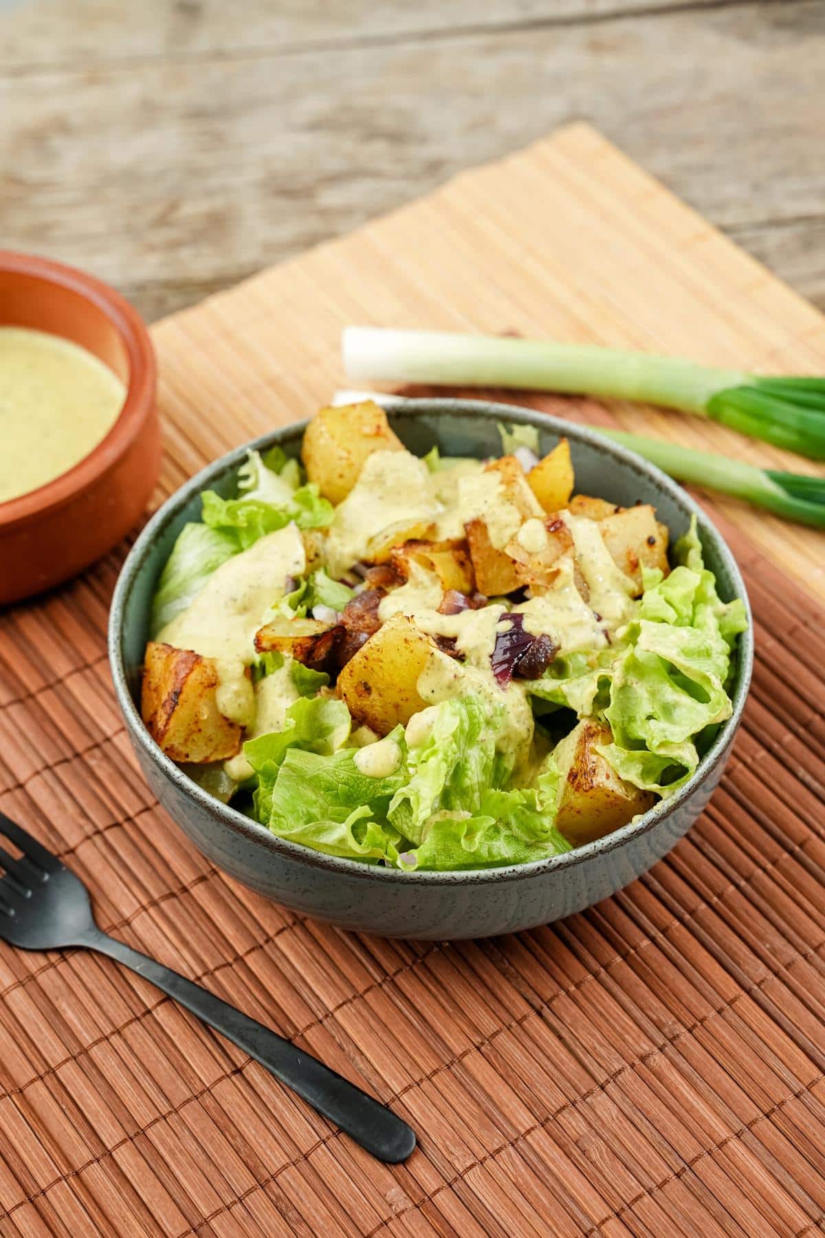 gray bowl of spicy potatoes with tahini dressing on bamboo placemat