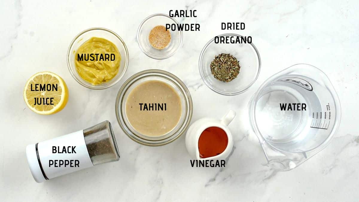 ingredients for tahini dressing in bowls on white table