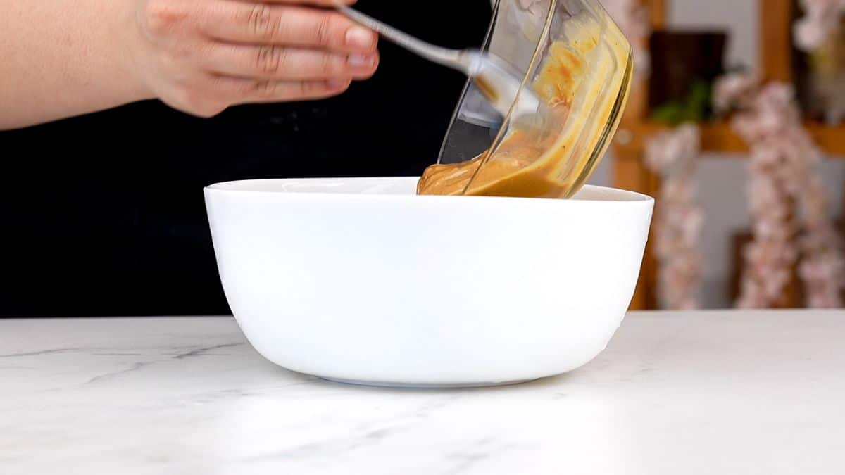 peanut butter being poured into white bowl on table