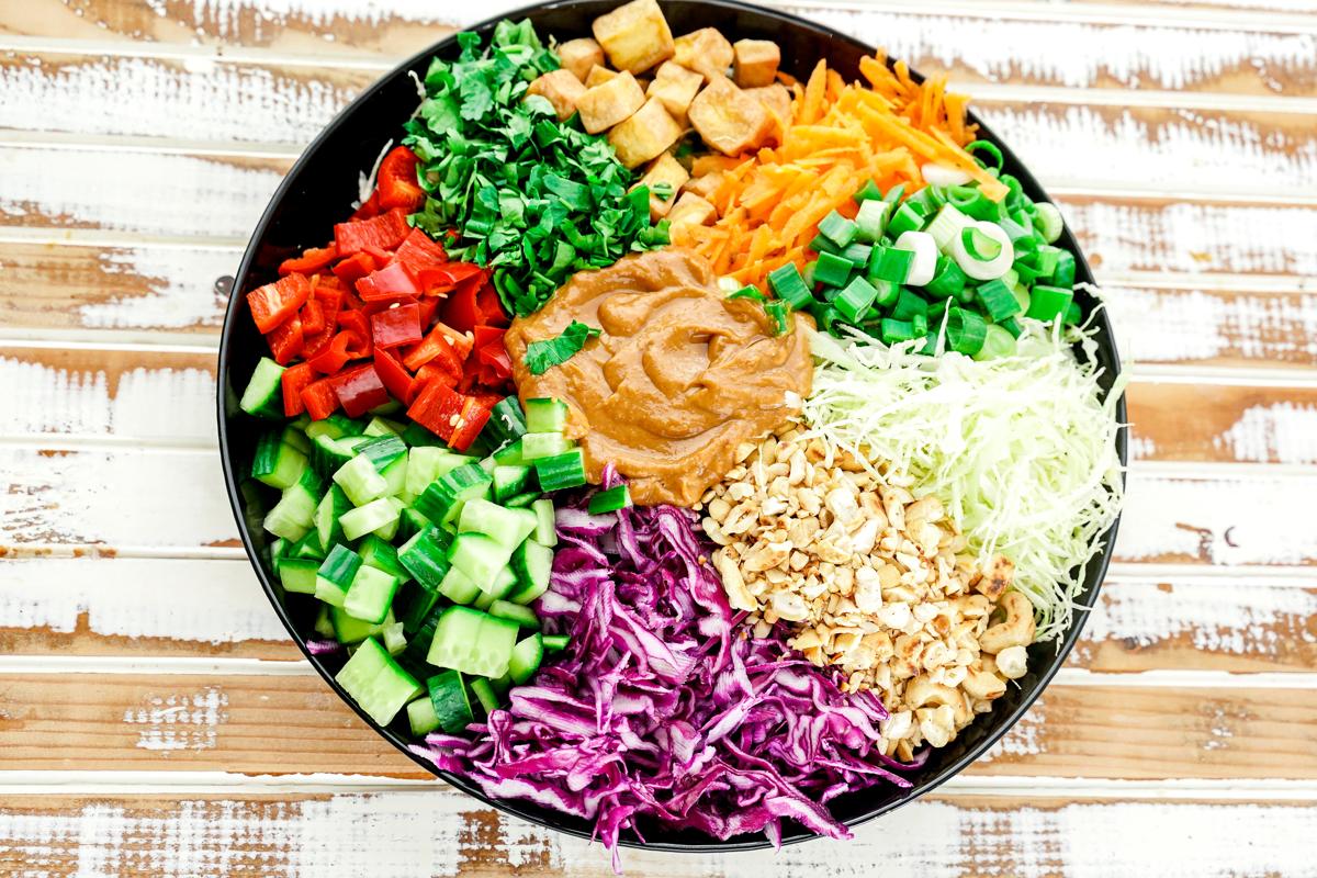 black bowl of salad with bright colors on rustic wood table