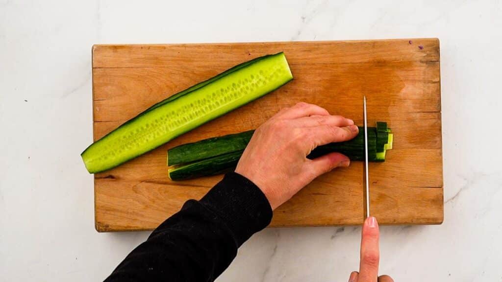cucumber being diced on wood cutting board