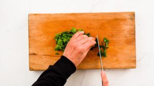 herbs being chopped on cutting board