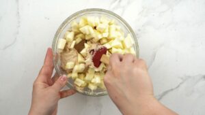 red spatula stirring apples in batter