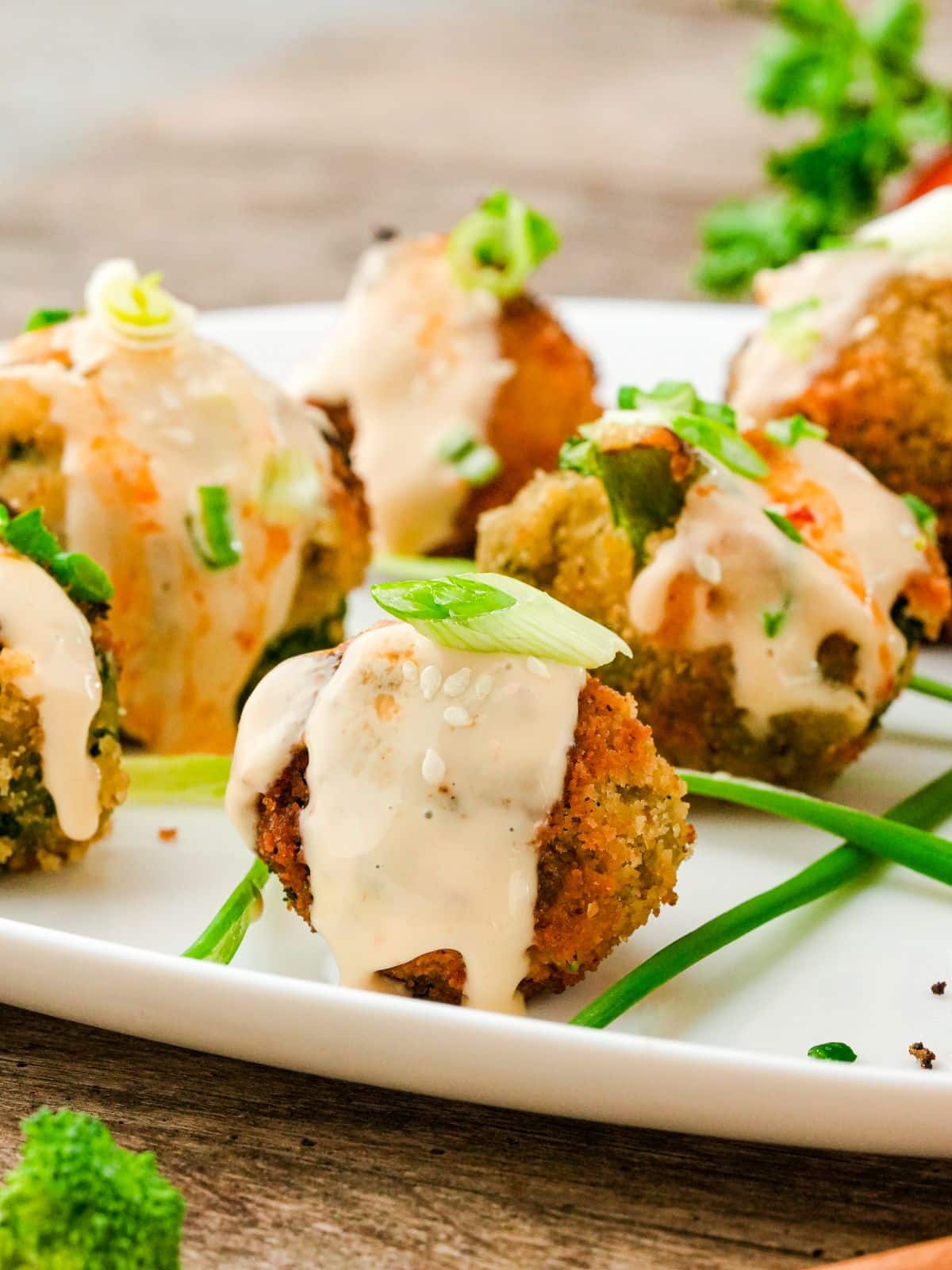 white plate of fried broccoli balls with sauce